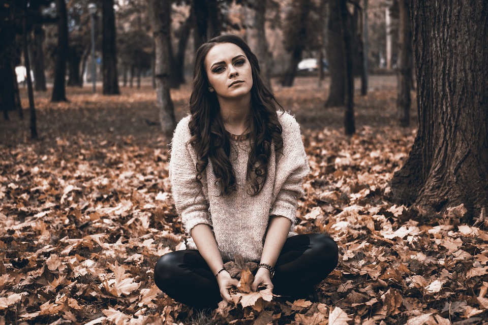 girl sitting on dried leaves